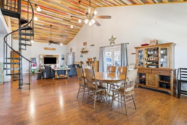 dining area with high vaulted ceiling, a ceiling fan, wood finished floors, french doors, and stairs