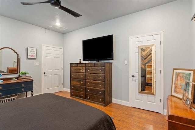 bedroom featuring visible vents, ceiling fan, baseboards, and wood finished floors