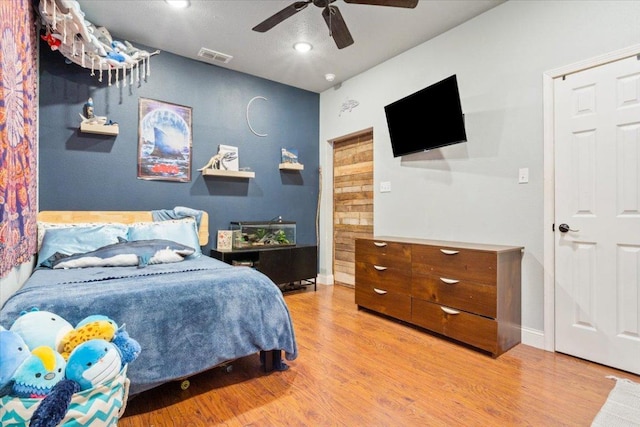 bedroom featuring a ceiling fan, wood finished floors, visible vents, and baseboards