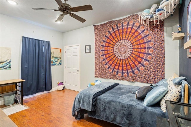 bedroom with baseboards, a ceiling fan, and wood finished floors