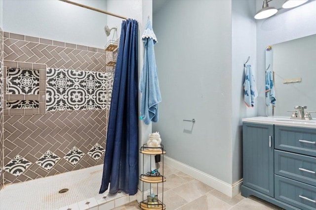 full bathroom featuring tile patterned flooring, vanity, baseboards, and a tile shower