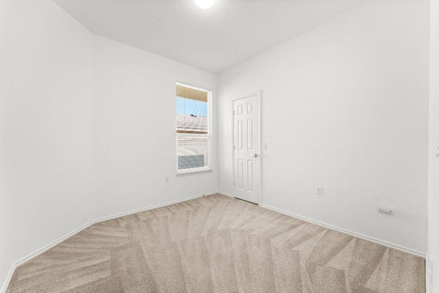 empty room featuring baseboards and light colored carpet