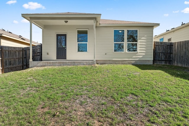 back of property with a lawn and a fenced backyard