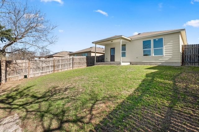 rear view of house featuring a yard and a fenced backyard