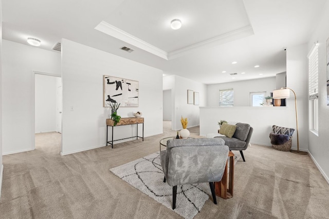 living room with visible vents, a raised ceiling, and light carpet