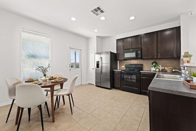 kitchen featuring visible vents, a sink, dark brown cabinetry, black appliances, and backsplash