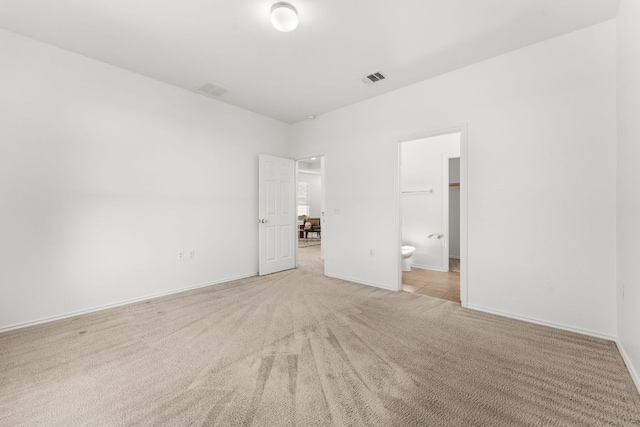 unfurnished room with visible vents, baseboards, and light colored carpet