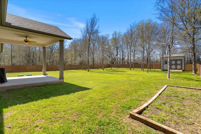 view of yard featuring an outbuilding, a storage unit, a ceiling fan, and a fenced backyard