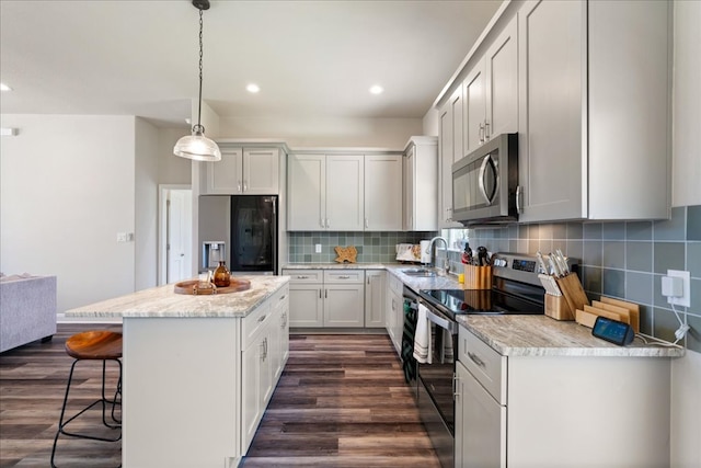 190 Waikakaaua Dr, Bastrop, TX 78602 - kitchen with stainless steel appliances, a sink, a center island, a breakfast bar, and dark wood-style floors