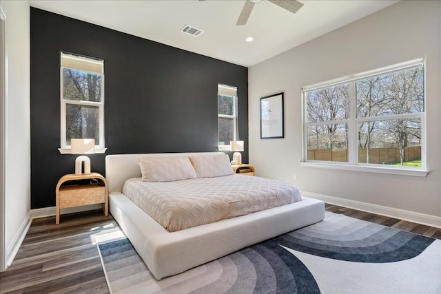 bedroom with visible vents, baseboards, dark wood-style floors, and an accent wall