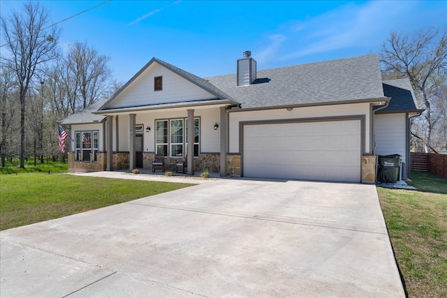 view of front of property with a front lawn, concrete driveway, covered porch, a chimney, and an attached garage