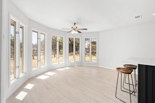 unfurnished sunroom with visible vents and ceiling fan