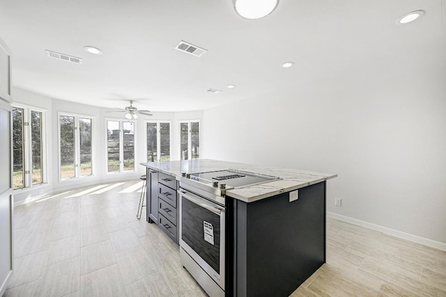 kitchen with dark cabinets, stainless steel electric stove, visible vents, and a kitchen island