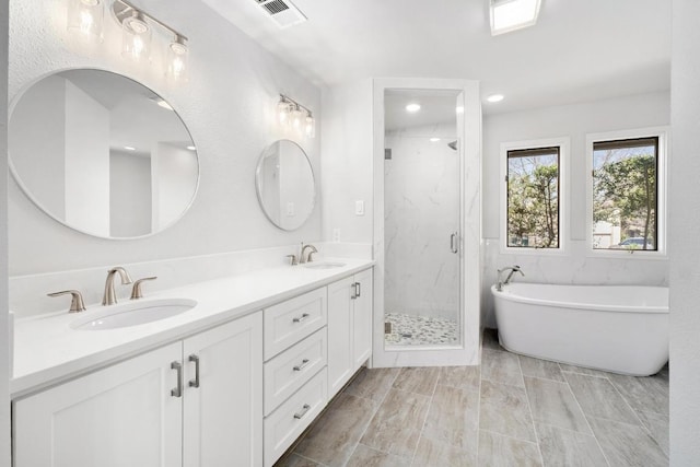 full bath featuring a marble finish shower, visible vents, double vanity, and a sink