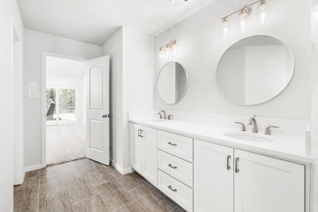 full bath featuring a sink, baseboards, and double vanity