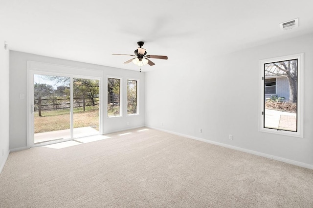 carpeted empty room featuring visible vents, baseboards, and a ceiling fan