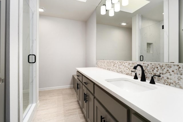 full bathroom featuring a marble finish shower, vanity, and baseboards