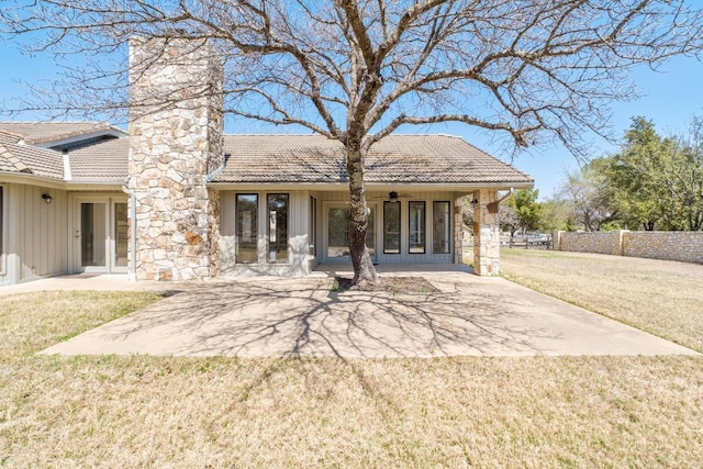 back of property with a tile roof, a lawn, a chimney, a patio area, and a ceiling fan