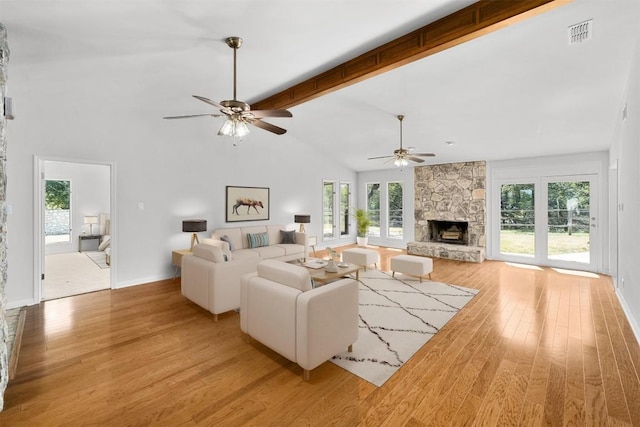 107 Boot Hl, Horseshoe Bay, TX 78657 - living area featuring light wood finished floors, a stone fireplace, ceiling fan, plenty of natural light, and beam ceiling