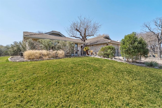 view of front of property featuring a tiled roof, a front lawn, and fence