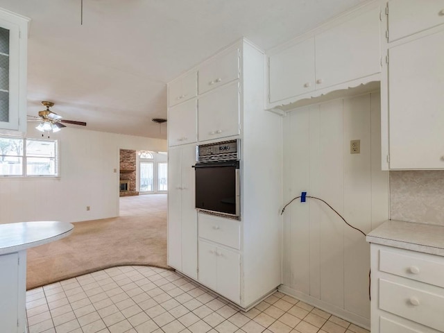 kitchen featuring oven, ceiling fan, open floor plan, light colored carpet, and light countertops