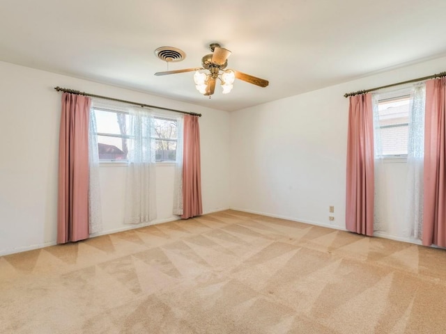 carpeted empty room featuring a ceiling fan, visible vents, and baseboards