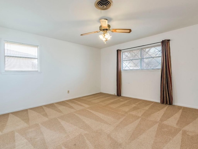 spare room featuring visible vents, light colored carpet, and ceiling fan