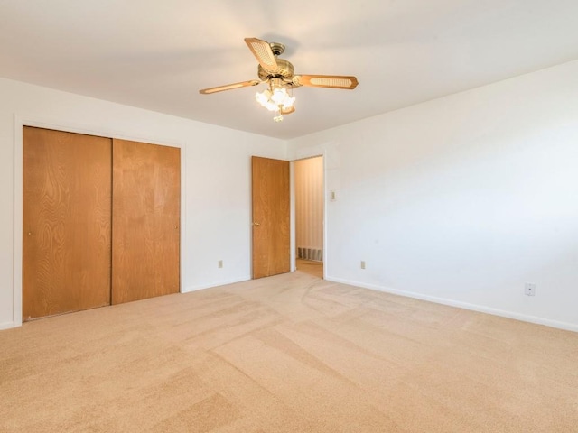 unfurnished bedroom with a closet, baseboards, light colored carpet, and a ceiling fan