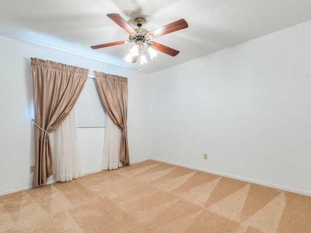 empty room featuring light carpet, baseboards, and a ceiling fan