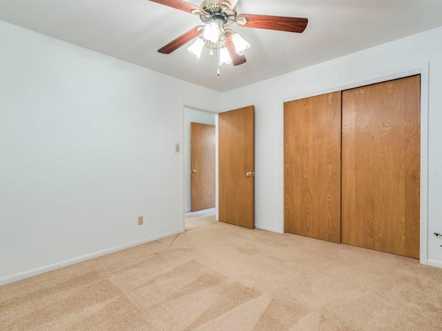 unfurnished bedroom featuring light carpet, baseboards, a ceiling fan, and a closet