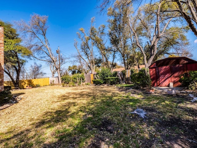 view of yard featuring a shed, an outdoor structure, and fence