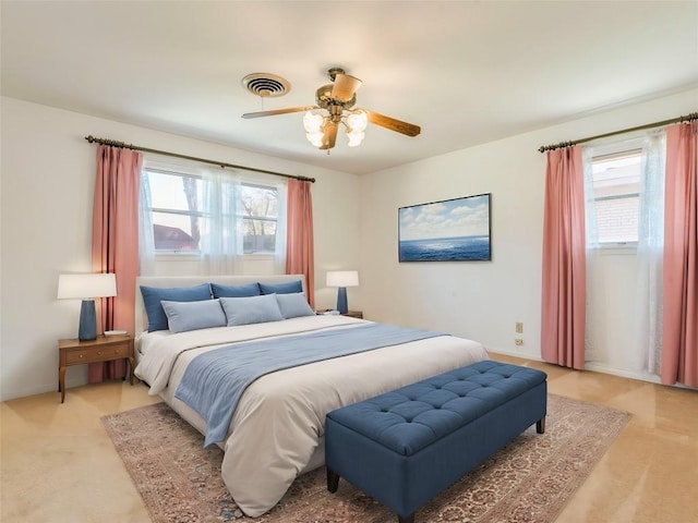 bedroom featuring visible vents, multiple windows, light colored carpet, and ceiling fan