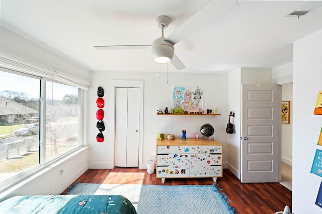 bedroom featuring visible vents, a ceiling fan, baseboards, and wood finished floors