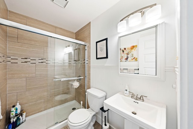 full bathroom with a wainscoted wall, visible vents, a stall shower, a sink, and toilet