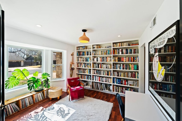 sitting room with bookshelves, recessed lighting, and wood finished floors