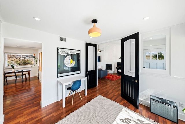 foyer with dark wood-style floors, plenty of natural light, a large fireplace, and visible vents