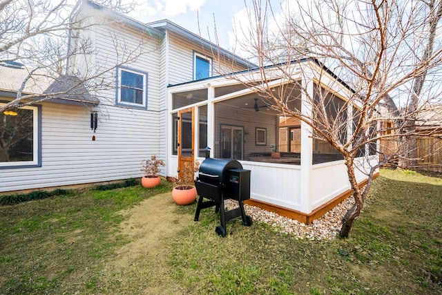 back of house featuring a lawn, fence, and a sunroom