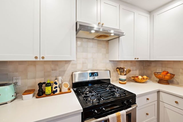 kitchen with under cabinet range hood, gas range, white cabinetry, and light countertops