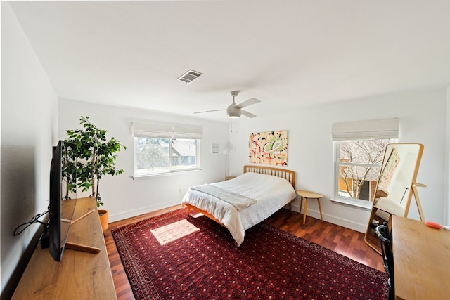 bedroom with visible vents, baseboards, wood finished floors, and a ceiling fan