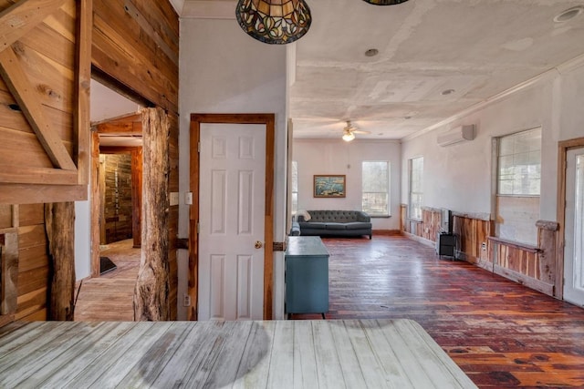 unfurnished bedroom with an AC wall unit, wood finished floors, and ornamental molding