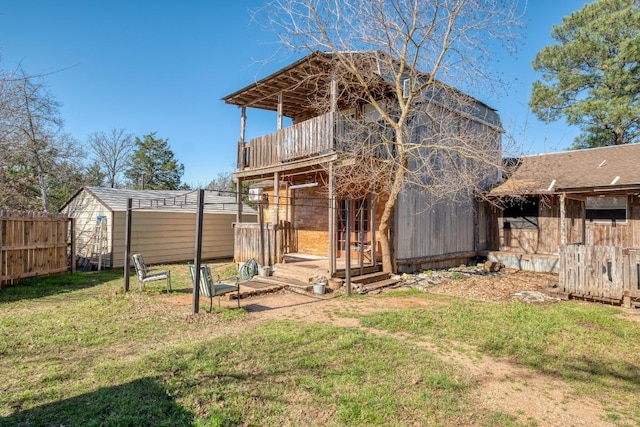 back of house with a lawn, a storage unit, an outdoor structure, and fence