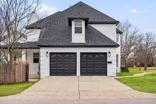 exterior space featuring a garage, a lawn, roof with shingles, and concrete driveway