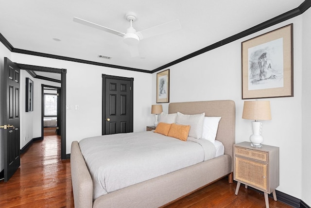 bedroom with visible vents, wood finished floors, and ornamental molding