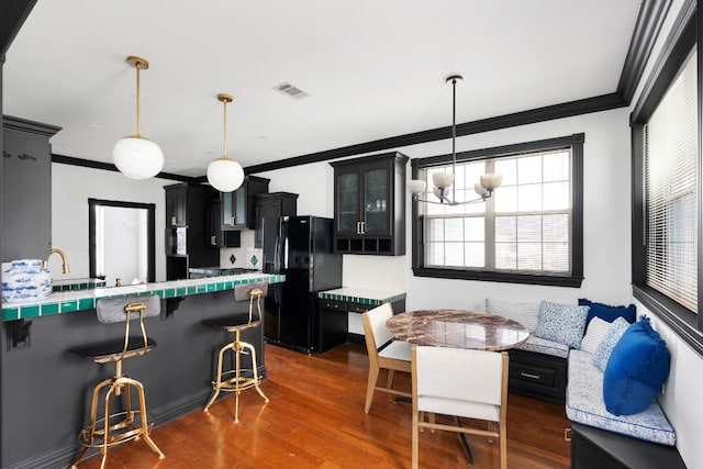 kitchen with visible vents, crown molding, breakfast area, a breakfast bar area, and black fridge