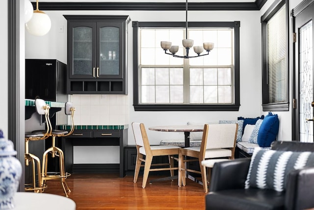 dining space featuring breakfast area, a notable chandelier, dark wood-style flooring, and crown molding