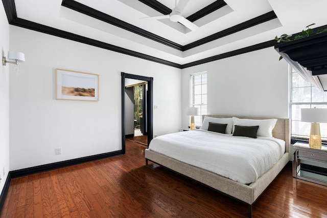 bedroom featuring a tray ceiling, wood-type flooring, baseboards, and crown molding