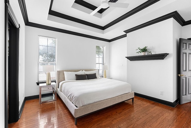 bedroom with a raised ceiling, ornamental molding, a ceiling fan, hardwood / wood-style flooring, and baseboards