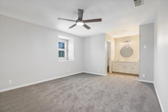 unfurnished bedroom with visible vents, baseboards, carpet, ensuite bathroom, and a ceiling fan