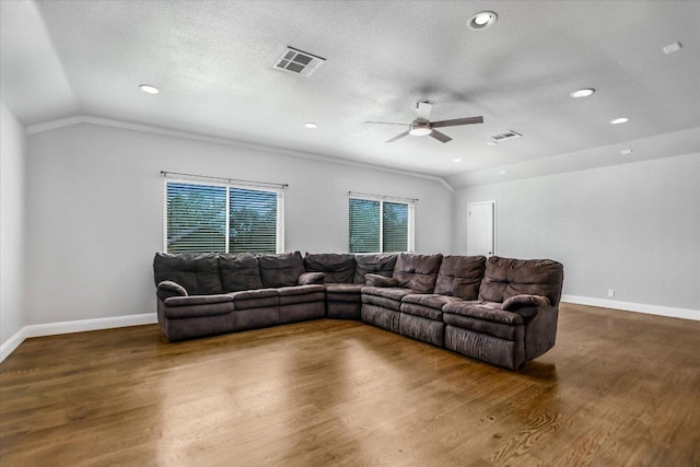 living area with vaulted ceiling, wood finished floors, visible vents, and a textured ceiling