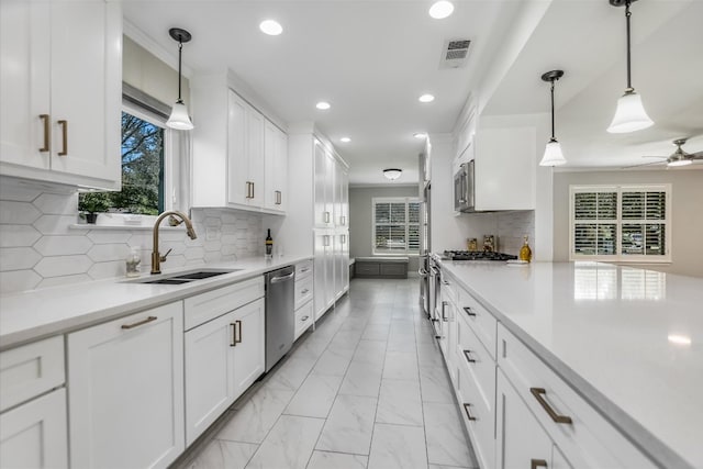 kitchen featuring visible vents, appliances with stainless steel finishes, white cabinets, marble finish floor, and a sink